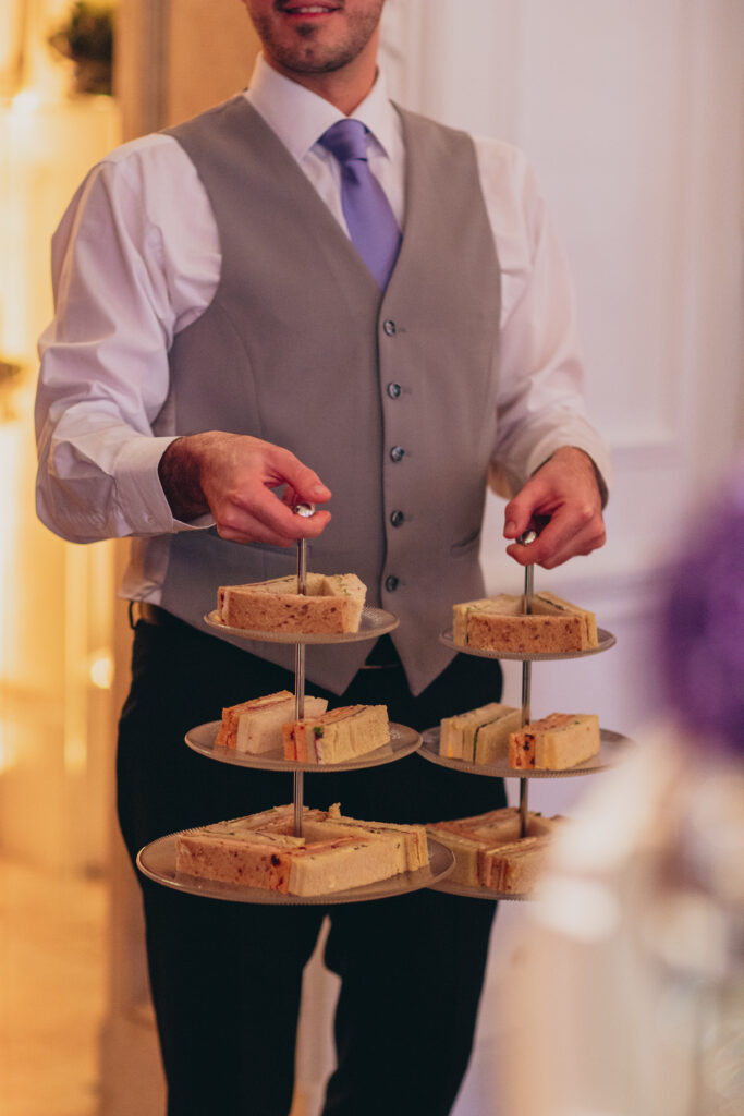 Waiter serving sandwiches from an afternoon tea stand